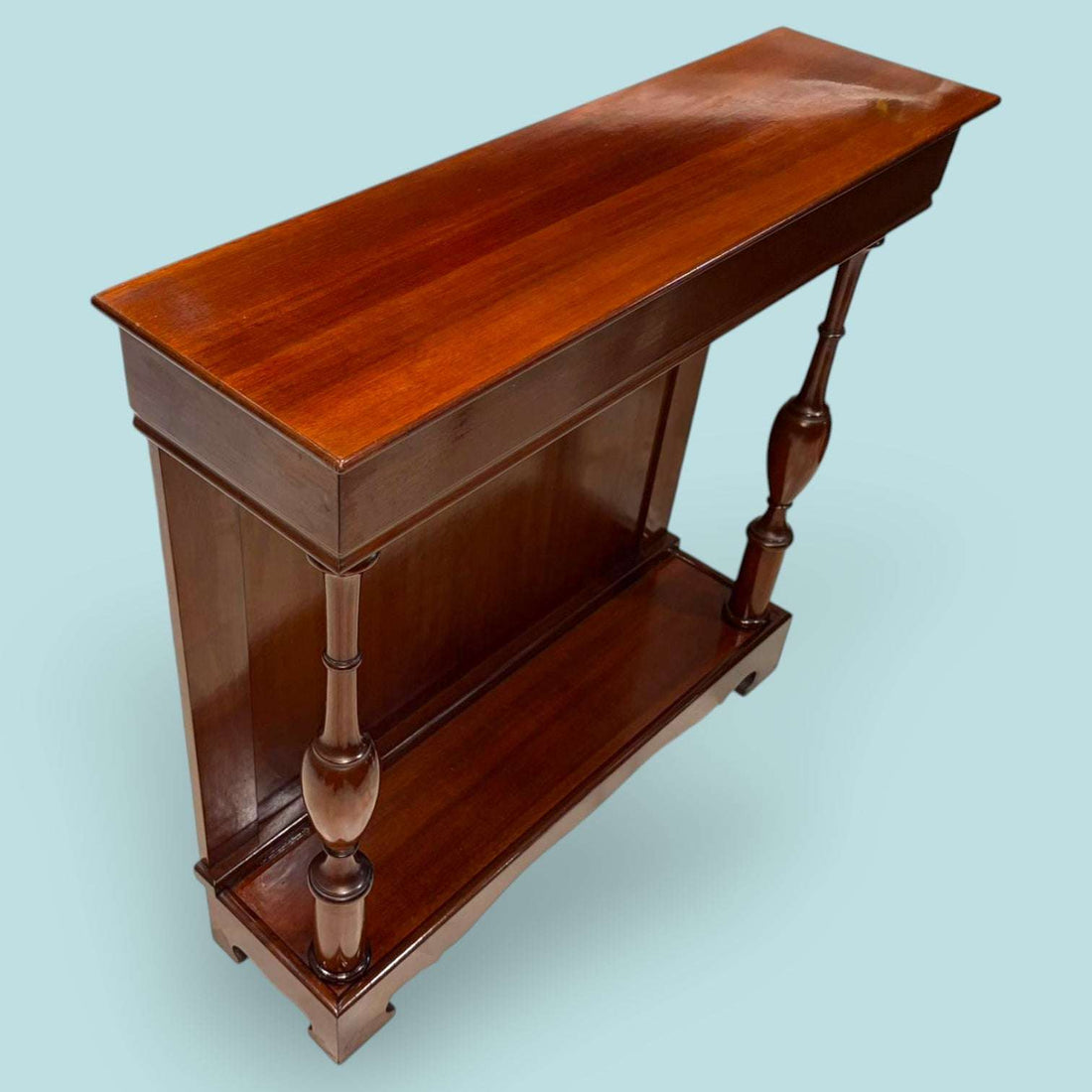 Esta Consola de caoba es una pieza auxiliar con gran valor decorativo, ideal para vestir recibidores, pasillos, salones, despachos o zonas de paso donde se busca un mueble estrecho, elegante y funcional. Su diseño alargado permite colocarla junto a una pared sin ocupar demasiado espacio, aportando calidez, orden y una estética clásica muy cuidada.

Su función original era servir como mueble de apoyo en entradas y salones, utilizado para colocar lámparas, jarrones, marcos, bandejas, llaves u objetos decorati