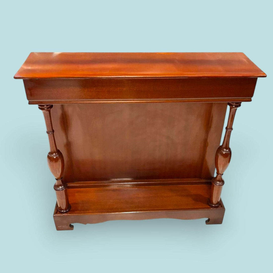 Esta Consola de caoba es una pieza auxiliar con gran valor decorativo, ideal para vestir recibidores, pasillos, salones, despachos o zonas de paso donde se busca un mueble estrecho, elegante y funcional. Su diseño alargado permite colocarla junto a una pared sin ocupar demasiado espacio, aportando calidez, orden y una estética clásica muy cuidada.

Su función original era servir como mueble de apoyo en entradas y salones, utilizado para colocar lámparas, jarrones, marcos, bandejas, llaves u objetos decorati