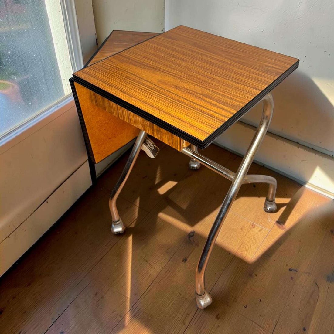 Su función original era servir como soporte auxiliar para máquina de escribir, permitiendo desplazarla con facilidad gracias a sus ruedas y ampliar la zona de trabajo mediante su lateral abatible. 