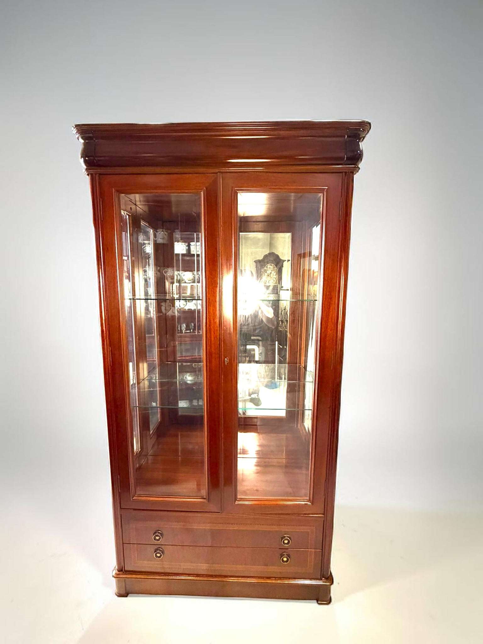 La VITRINA antigua de caoba es una pieza elegante y vertical, pensada originalmente para proteger y exponer objetos especiales como porcelanas, cristalerías, figuras decorativas, libros selectos o piezas de colección.
