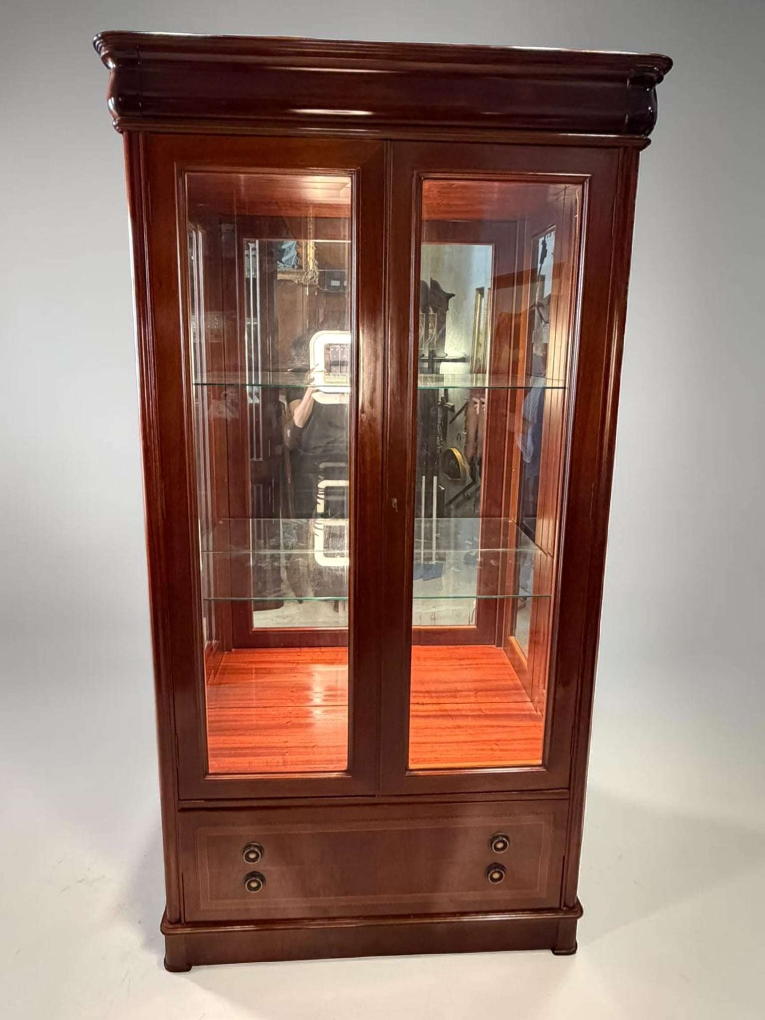  La parte frontal presenta dos grandes puertas de cristal enmarcadas en madera, que permiten ver el interior con claridad y dar protagonismo a los objetos expuestos.