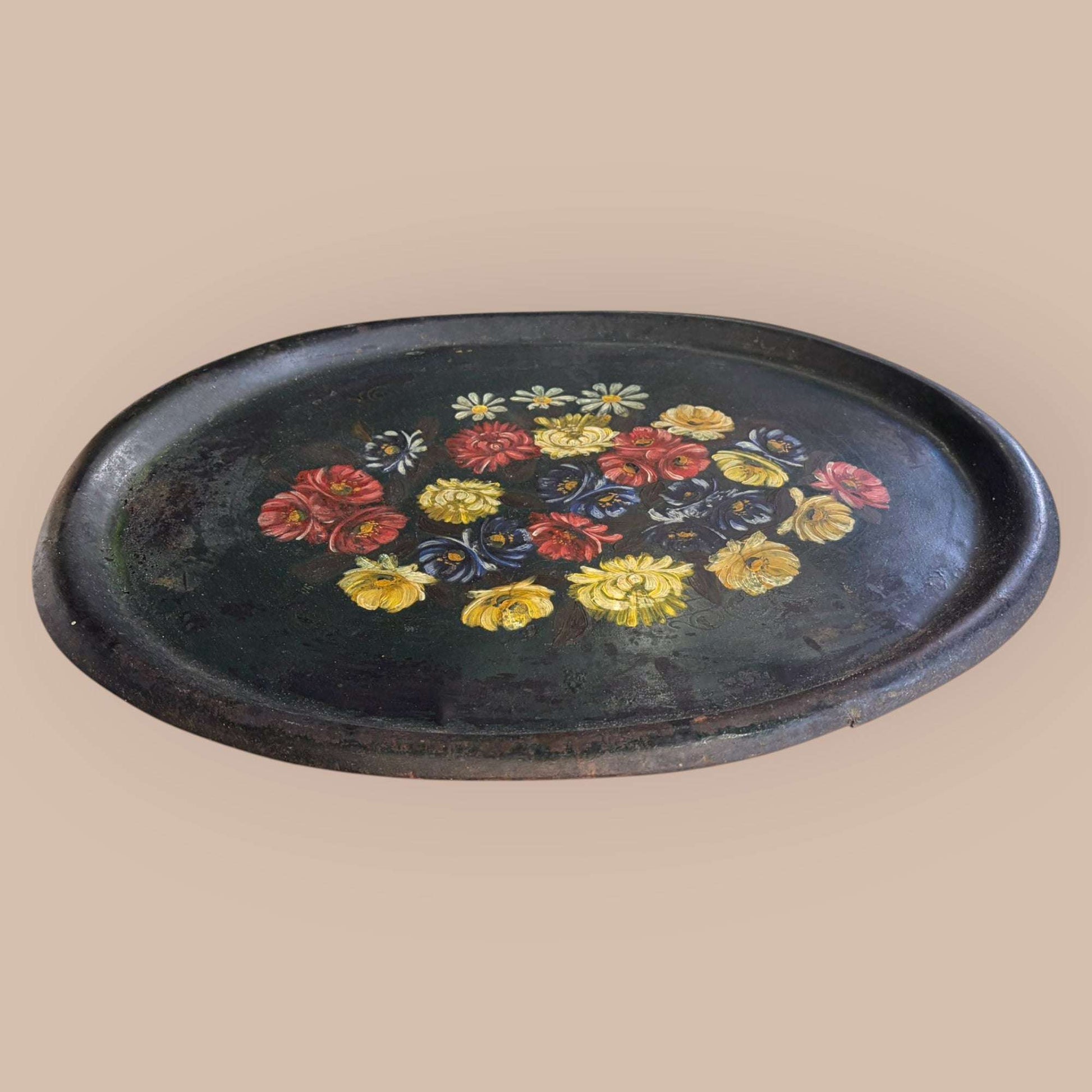 Esta Bandeja antigua de tole, realizada en metal pintado, es una pieza decorativa con gran personalidad visual.