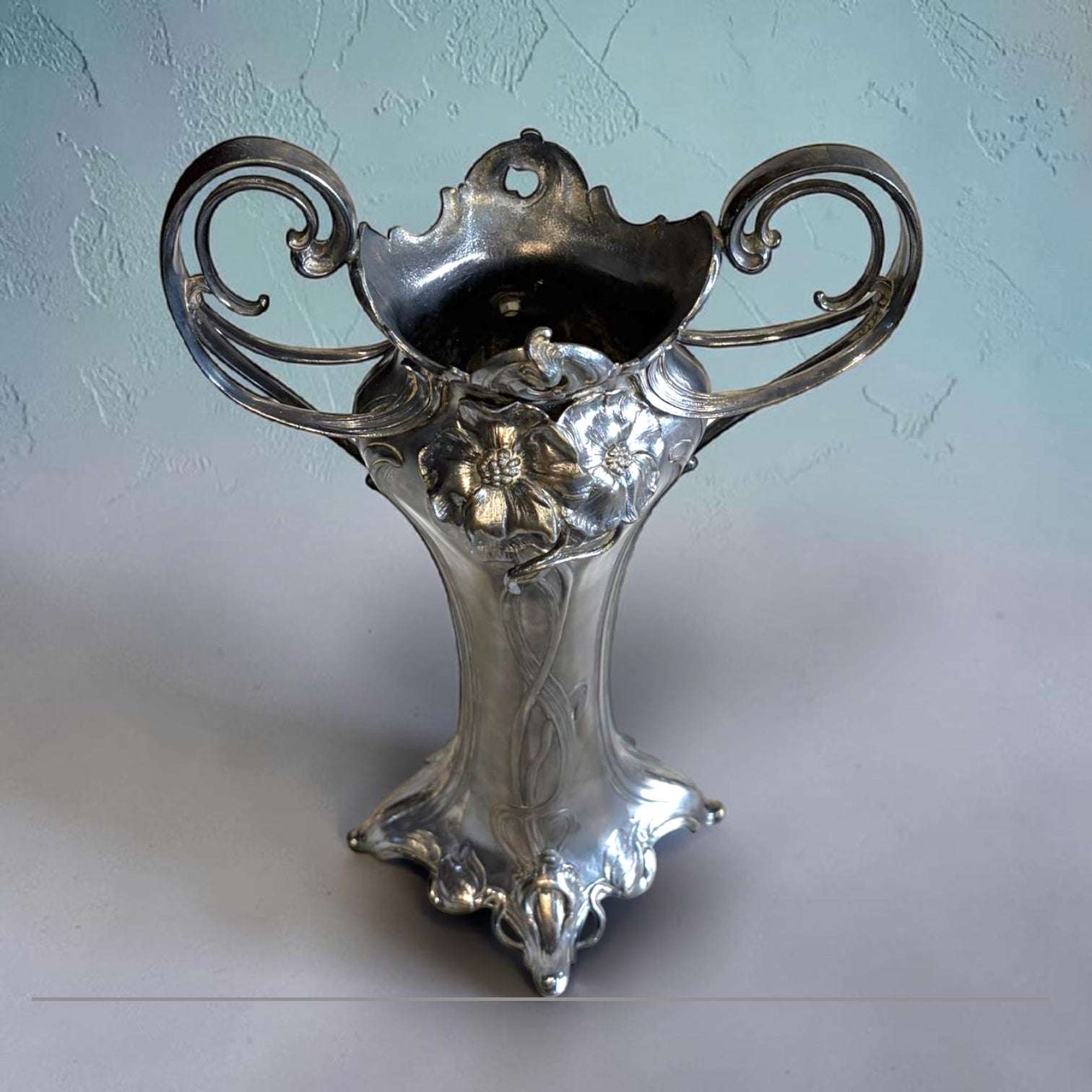 Su función original era contener flores naturales o secas, aportando altura, elegancia y protagonismo a una mesa, consola, recibidor o aparador. 