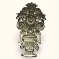 Su diseño floral recuerda a los ramos decorativos tradicionales, con una composición simétrica, volumen y un acabado metálico que encaja muy bien en interiores clásicos, vintage, eclécticos o románticos.