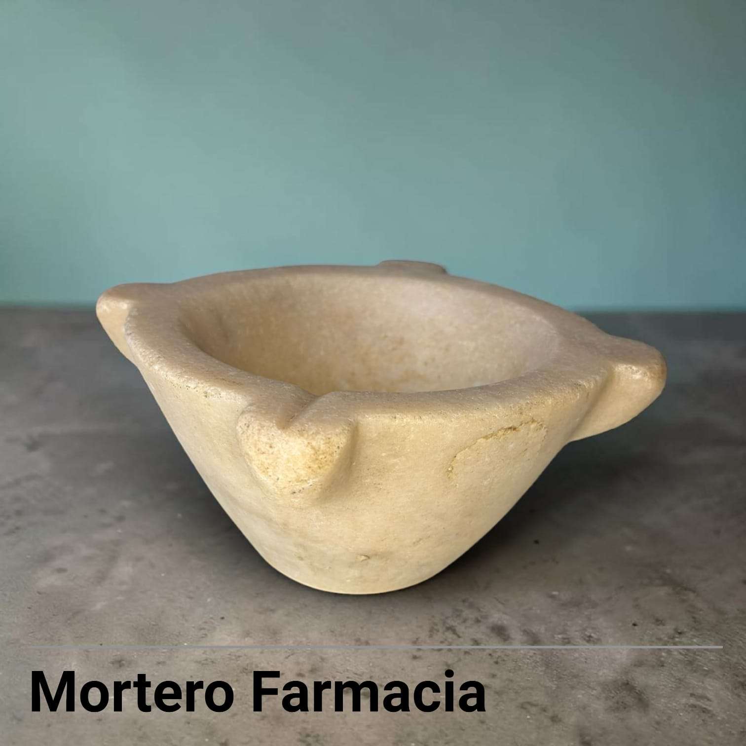 El mármol muestra tono crema envejecido, pátina amarillenta interior, pequeñas manchas, desgaste superficial y textura natural de la piedra.