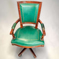 El sillón presenta asiento amplio tapizado, respaldo alto con panel verde, reposabrazos tapizados y estructura de caoba con vetas cálidas.