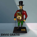 Representa a un relojero con sombrero de copa negro, levita roja, pantalón verde, bastón lateral y una pieza horaria situada en el pecho, convirtiéndose en un objeto lleno de carácter, color y fuerza visual.
