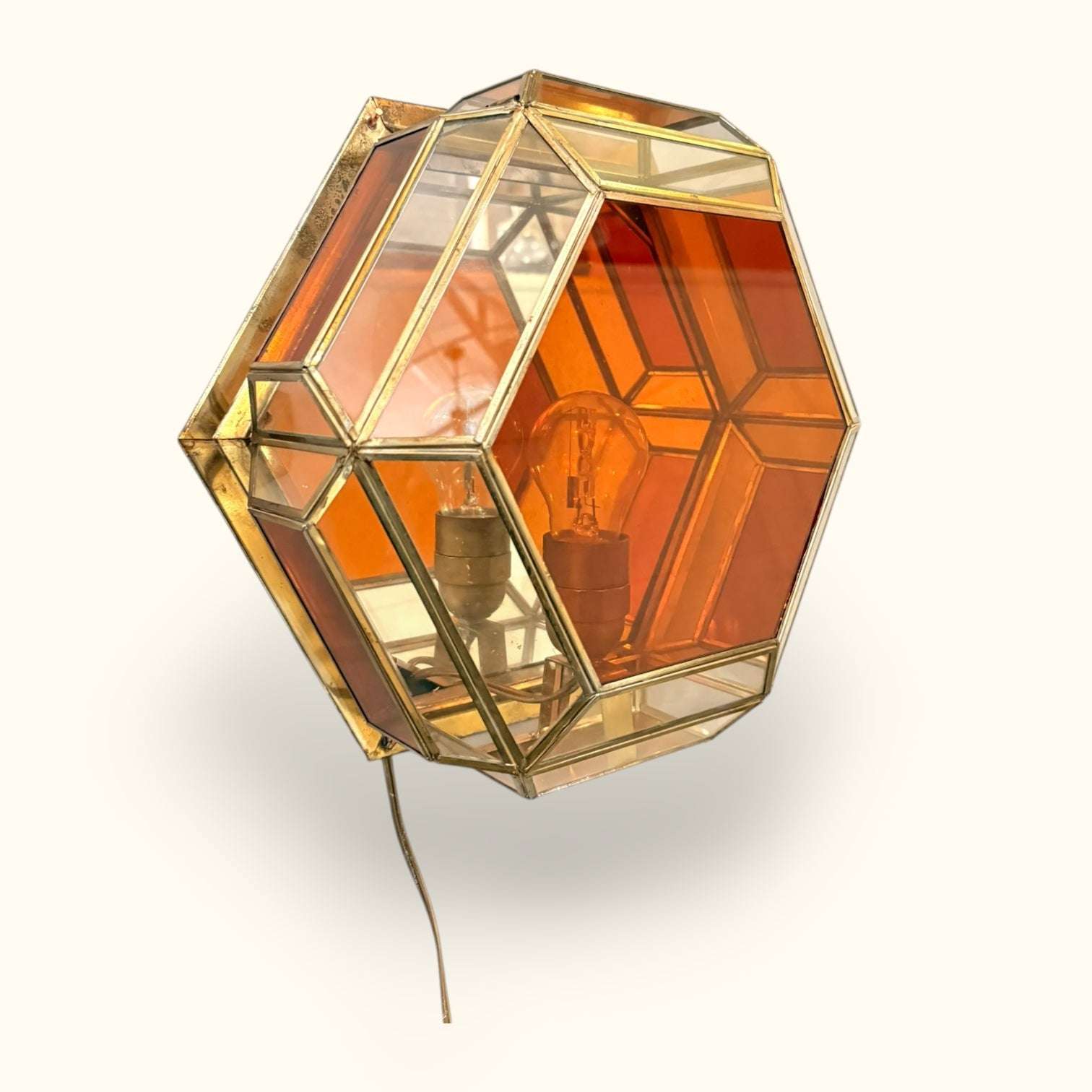 Esta Lámpara de pared es una pieza decorativa de estilo granadino, realizada con estructura metálica dorada y paneles de cristal en tonos transparentes y ámbar. 