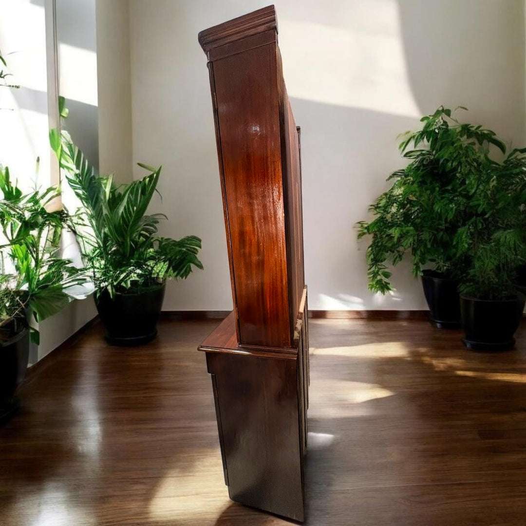 La Vitrina presenta una estructura en madera de caoba con acabado cálido y brillo natural, visible en sus molduras, puertas y cajones.