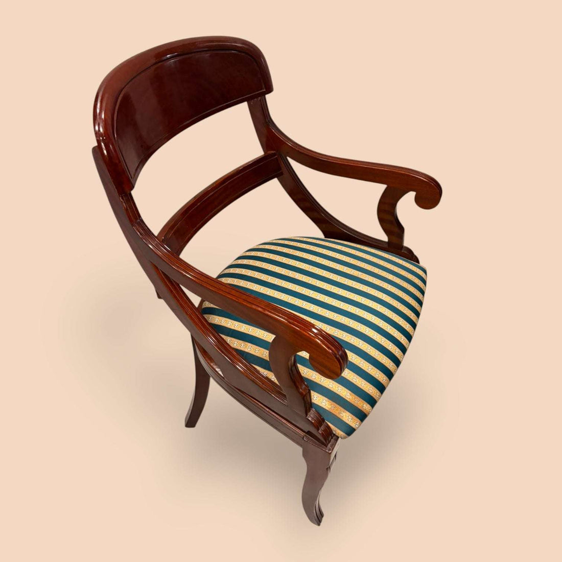 Este Sillón de estilo Biedermeier, datado alrededor de 1890, es una pieza antigua de gran elegancia, fabricada en madera de caoba y acompañada por un asiento tapizado a rayas en tonos verde azulado, dorado y crema.