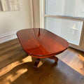 La mesa comedor de caoba destaca por su brillo, por la belleza de su tablero ovalado y por el trabajo ornamental de su base central.