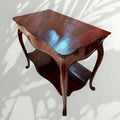 Esta mesa auxiliar de caoba destaca por su diseño elegante, sus líneas curvas y su acabado brillante, ideal para aportar un toque clásico y distinguido a cualquier estancia.