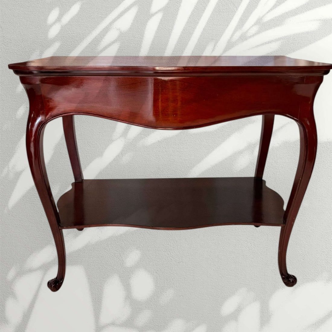 Esta mesa auxiliar de caoba destaca por su diseño elegante, sus líneas curvas y su acabado brillante, ideal para aportar un toque clásico y distinguido a cualquier estancia.