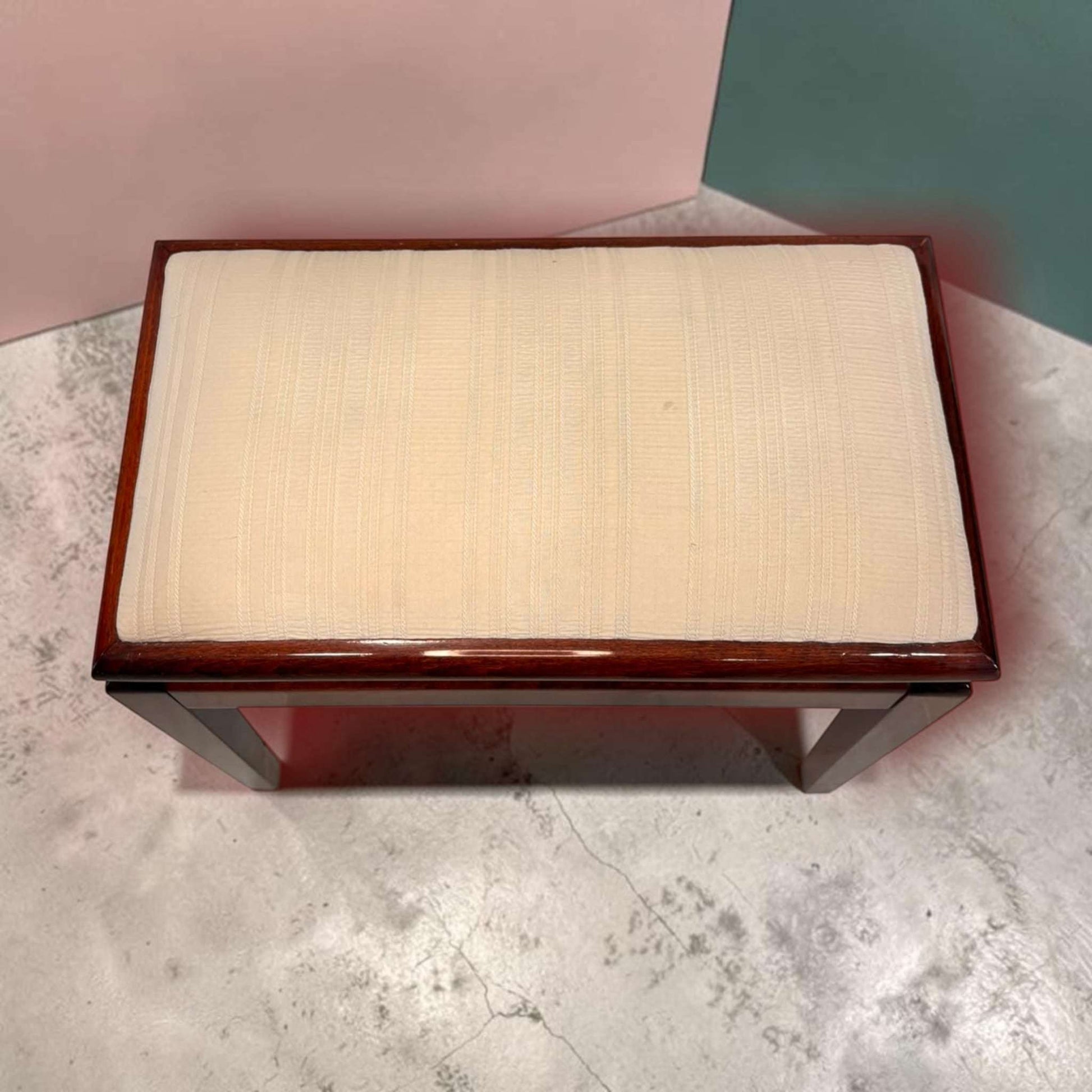 Detalle del respaldo de la banqueta de caoba con asiento tapizado beige, estructura de madera oscura y acabado pulido.