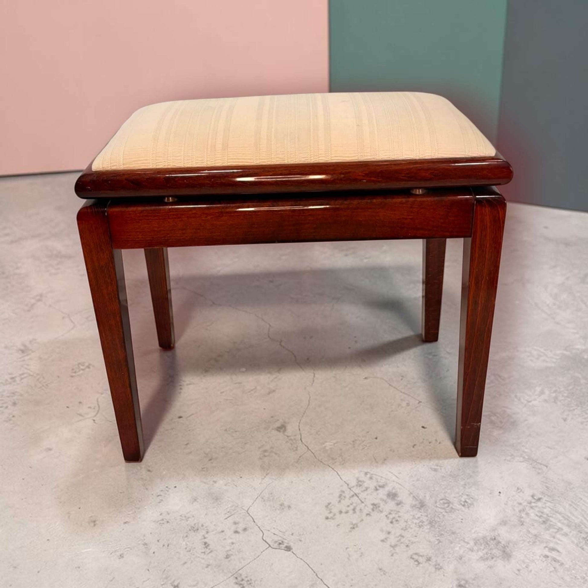 Banqueta de caoba con asiento tapizado en color beige y almacenaje, estructura de madera oscura, ideal para dormitorio o recibidor.