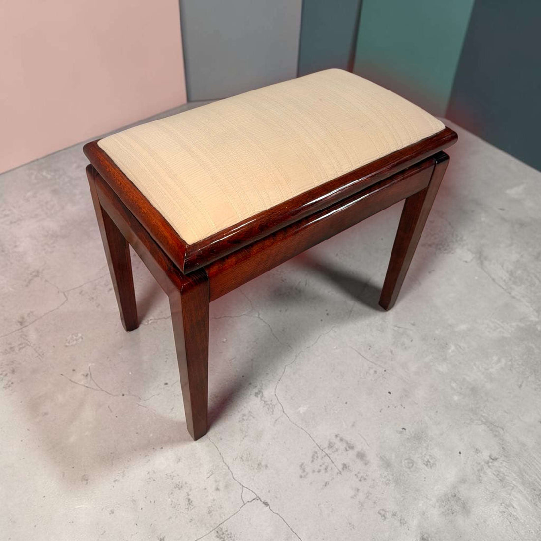 Banqueta de caoba con asiento tapizado en color beige y almacenaje, estructura de madera oscura, ideal para dormitorio o recibidor.