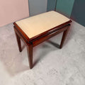 Vista superior de la banqueta de caoba con asiento tapizado beige, estructura de madera oscura y detalles de almacenaje en madera.