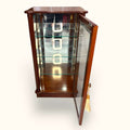 Vitrina de caoba con cristal, estructura de madera de tono marrón oscuro, con detalles tallados y un colgador con borla decorativa en el lado.