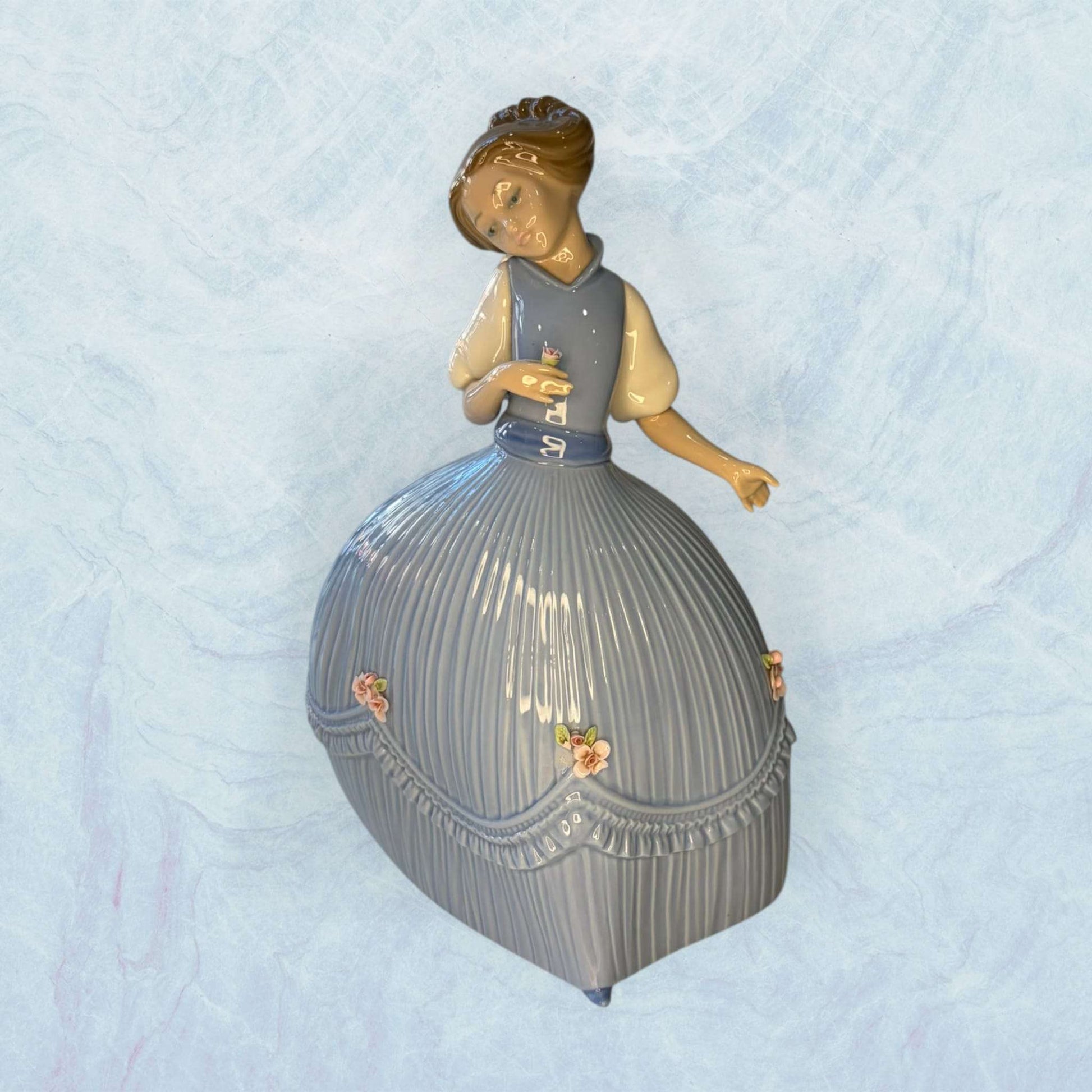 Esta Porcelana Lladró representa una delicada niña con vestido azul, una pieza decorativa pensada para quienes valoran la elegancia de la porcelana española, el coleccionismo y los objetos con sensibilidad artística. 