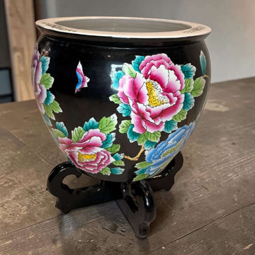 Jardinera china de porcelana negra con flores vibrantes en tonos rosa, azul y verde, decorada con soporte de madera, pieza decorativa oriental.