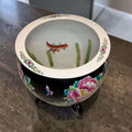 Base de la jardinera china de porcelana con sello de marca en rojo, mostrando desgaste y detalles de la decoración floral y soporte de madera.