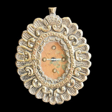 Relicario antiguo con fragmento de túnica bordada, marco decorativo en relieve con detalles dorados y perlas, pieza religiosa de colección.