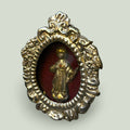 Relicario del Niño Jesús en metal plateado con fondo de terciopelo rojo, pieza religiosa antigua y decorativa con detalles elaborados en la orilla