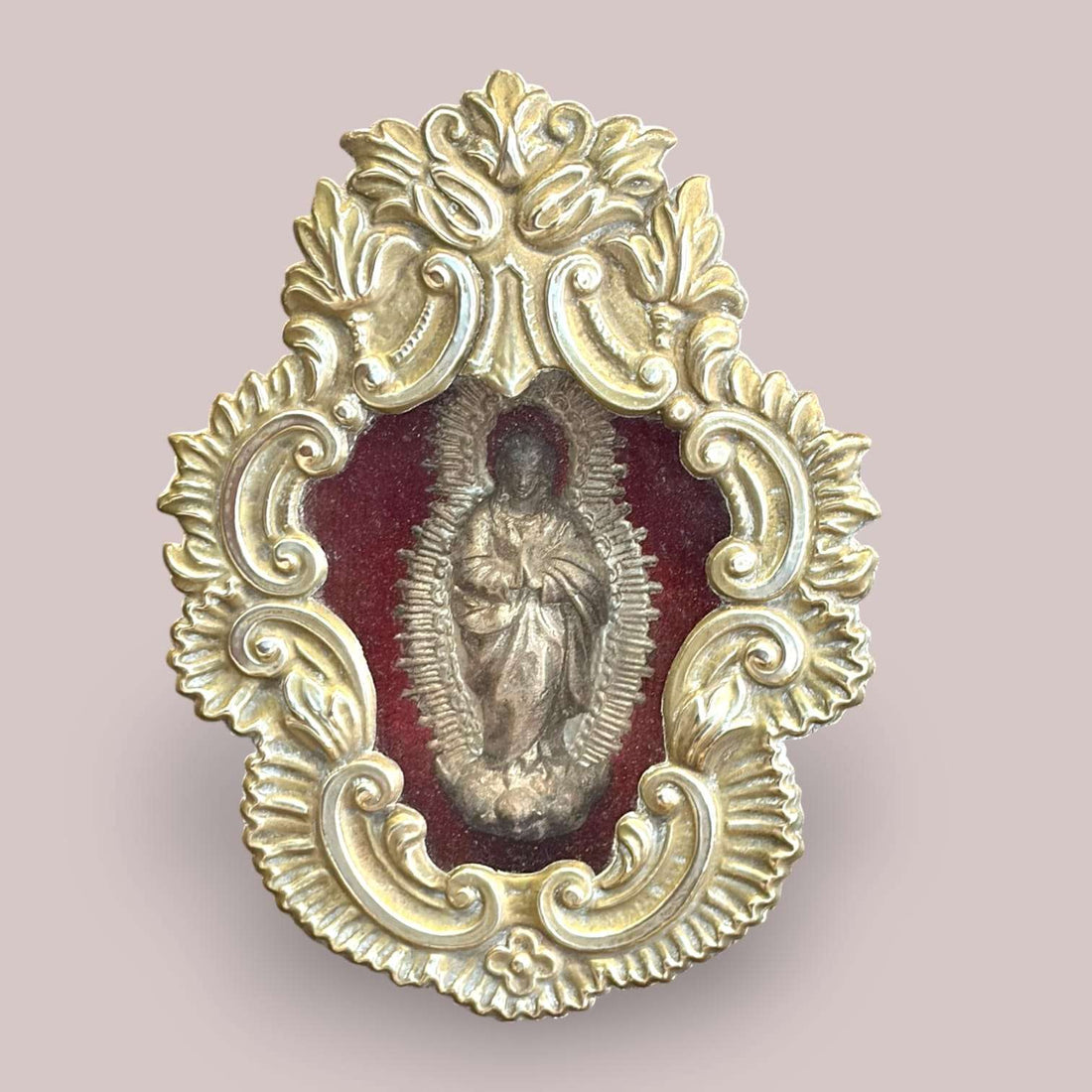 Relicario de la Inmaculada en metal plateado con fondo de terciopelo rojo, pieza religiosa antigua y decorativa, con detalles ornamentales elaborados.