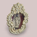 Vista frontal del relicario con imagen de la Virgen de la Inmaculada en relieve, rodeada de un marco decorativo en metal plateado con fondo de terciopelo rojo.
