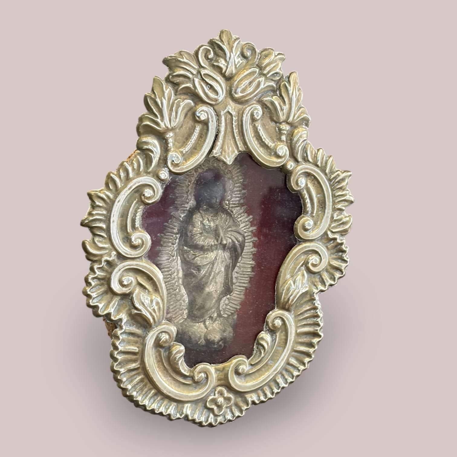Vista frontal del relicario con imagen de la Virgen de la Inmaculada en relieve, rodeada de un marco decorativo en metal plateado con fondo de terciopelo rojo.