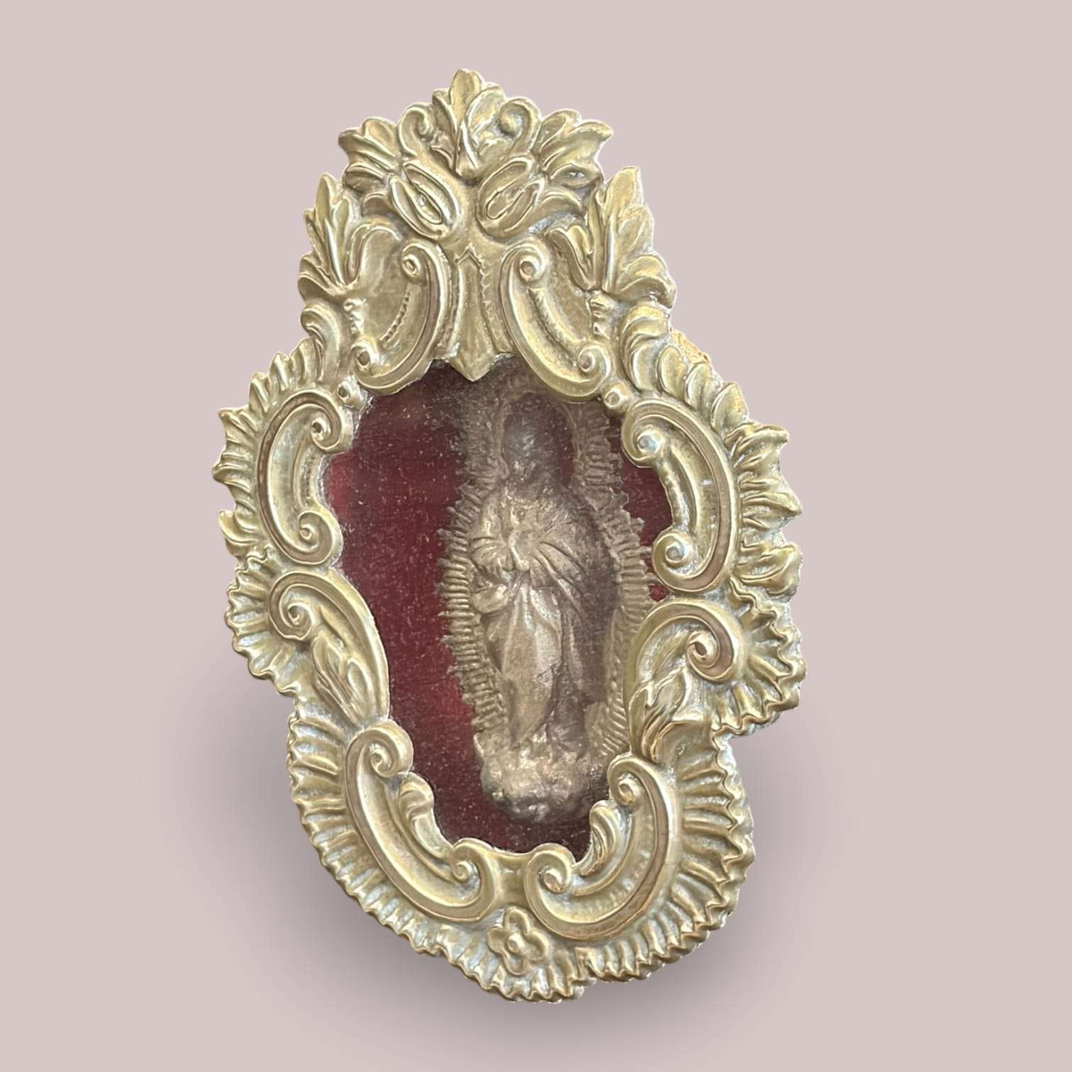 Detalle del relicario de la Inmaculada en metal plateado, resaltando la figura de la Virgen en relieve y el fondo de terciopelo rojo, con ornamentación dorada.