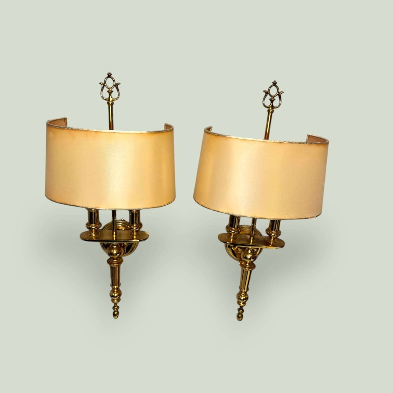 Pareja de apliques dorados de pared con pantalla curva en metal, ideales para decorar salones, entradas o dormitorios con estilo clásico.