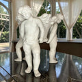 Perspectiva lateral del centro de mesa de porcelana con querubines, figura artística y decorativa para ambientes elegantes.