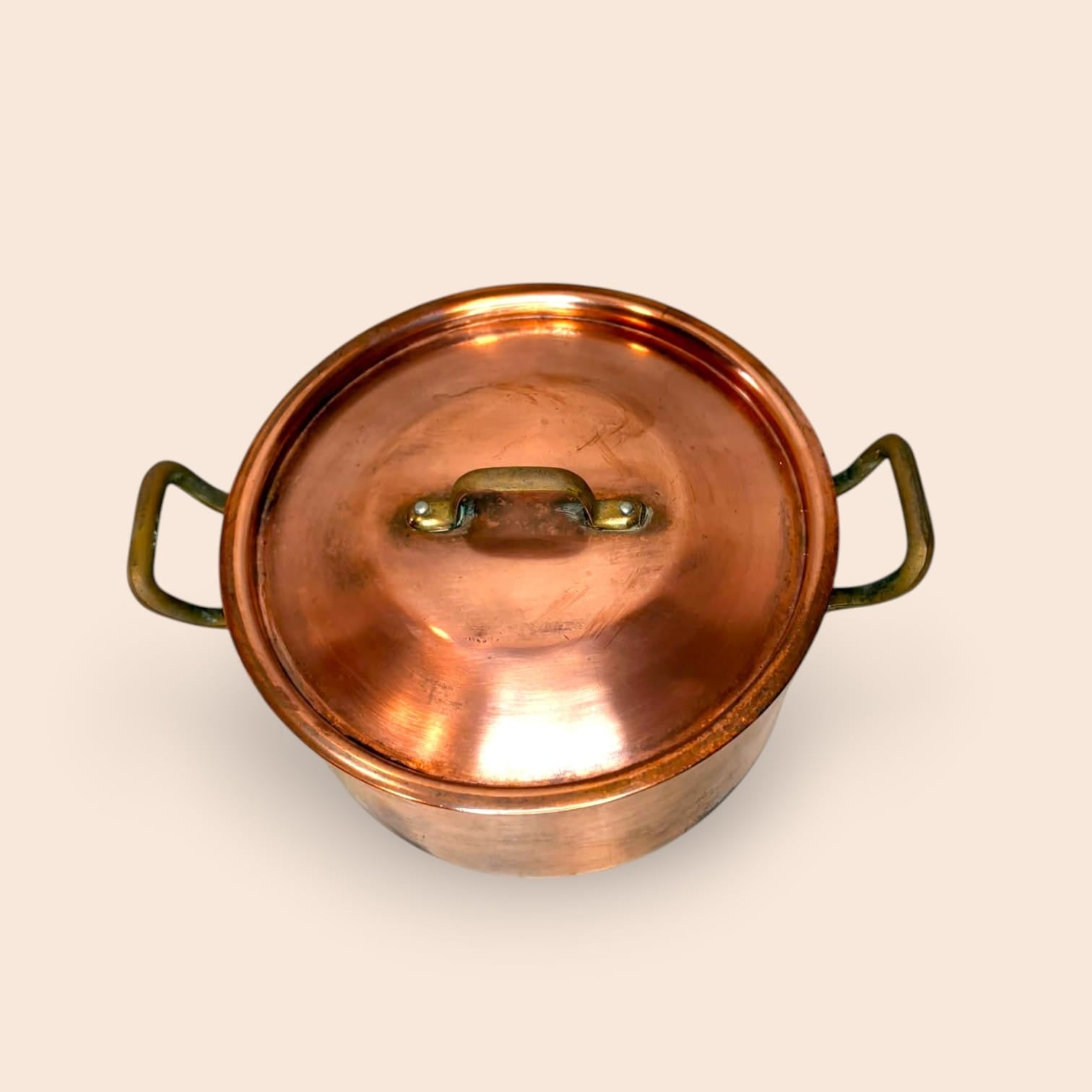 Las asas laterales contrastan con el cobre mediante un tono dorado envejecido.
