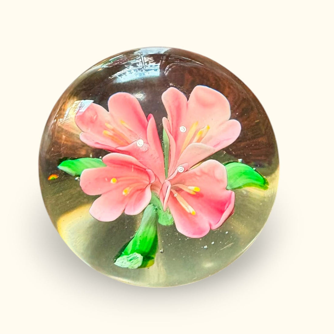 El pisapapeles de cristal Murano concentra su atractivo en el contraste entre el cristal transparente y la floración rosa y verde del interior. 