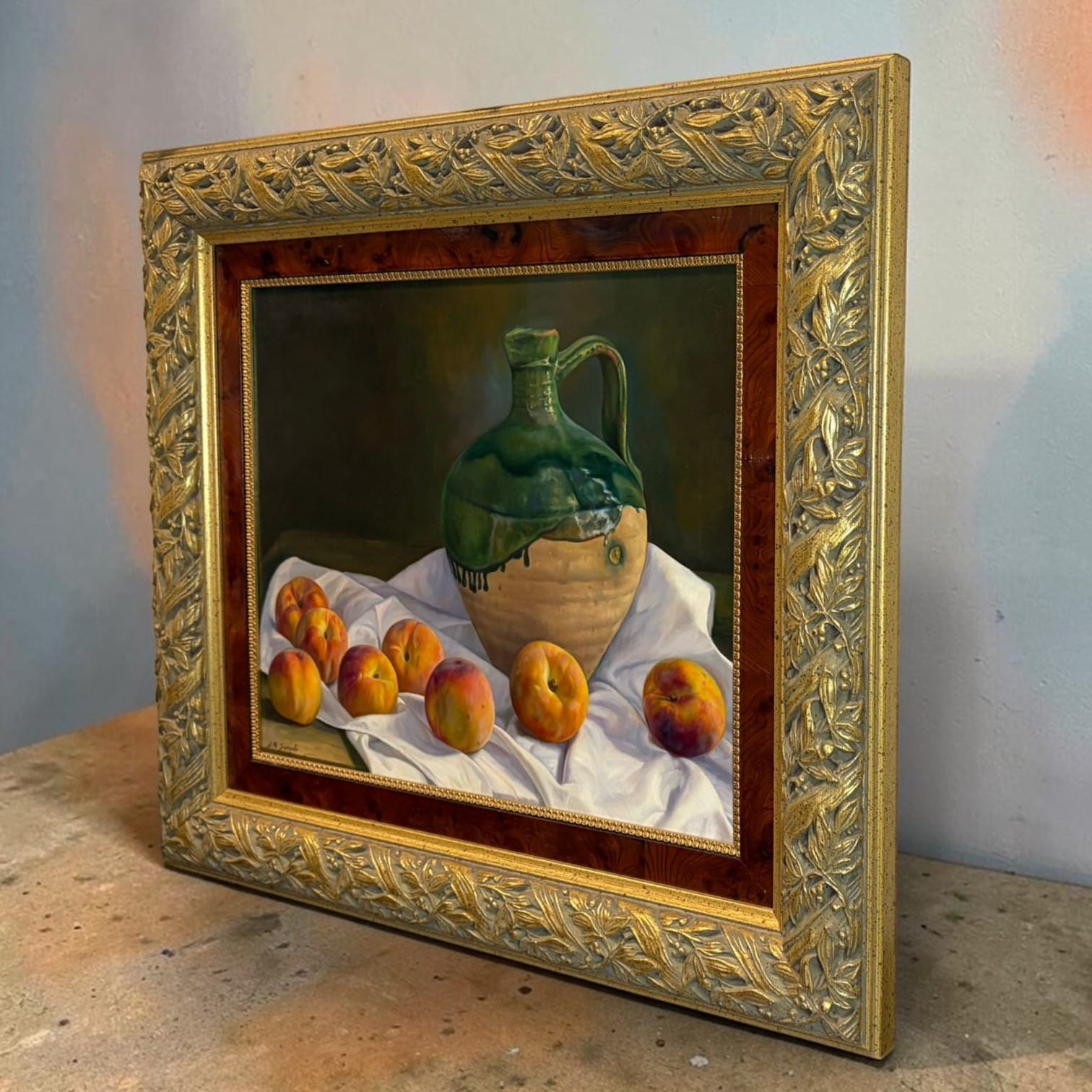 Una pintura figurativa de gusto clásico en la que destacan el contraste entre el fondo oscuro, la cerámica verde y los tonos cálidos de las frutas.

