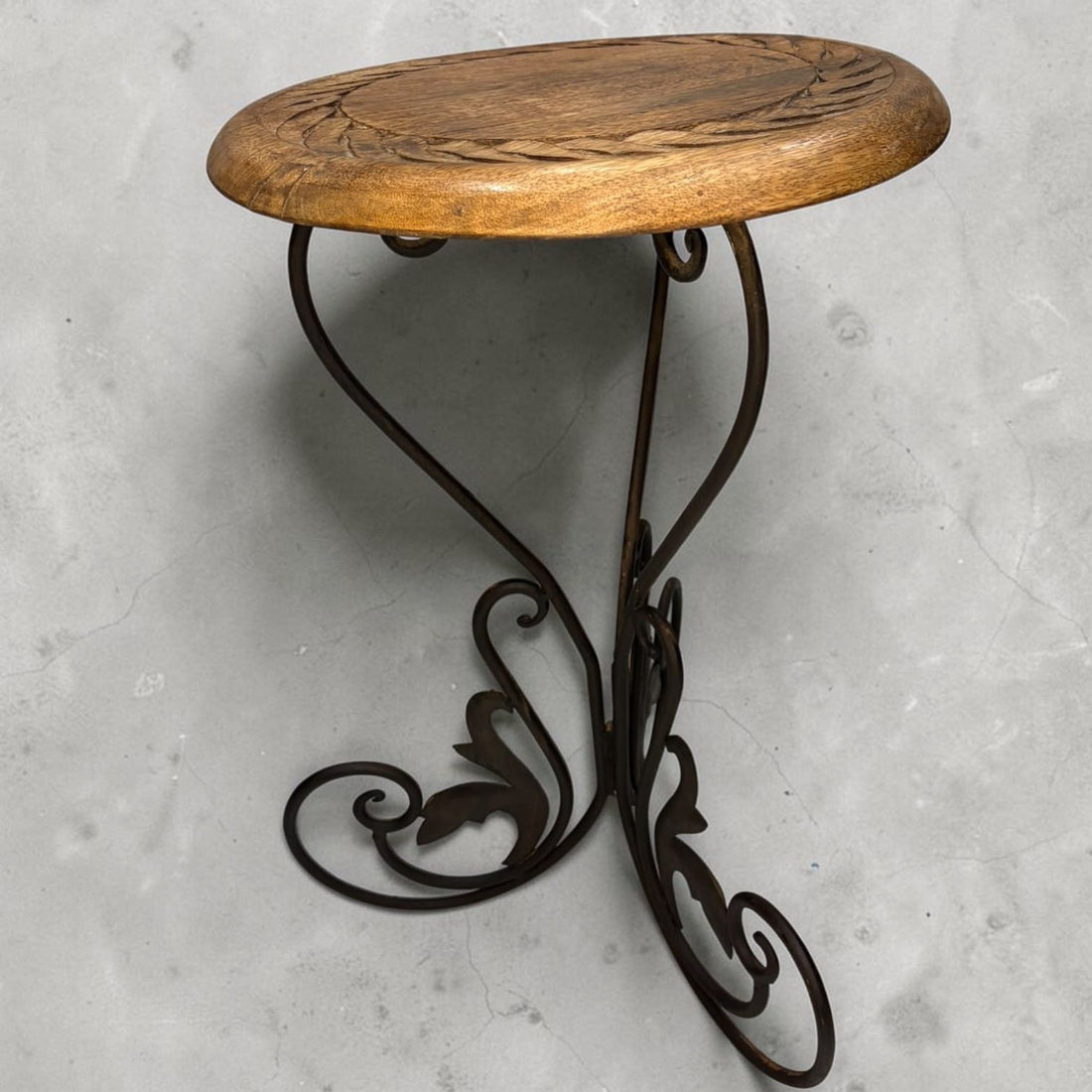 Esta mesa auxiliar combina una tapa de madera tallada con una estructura de 