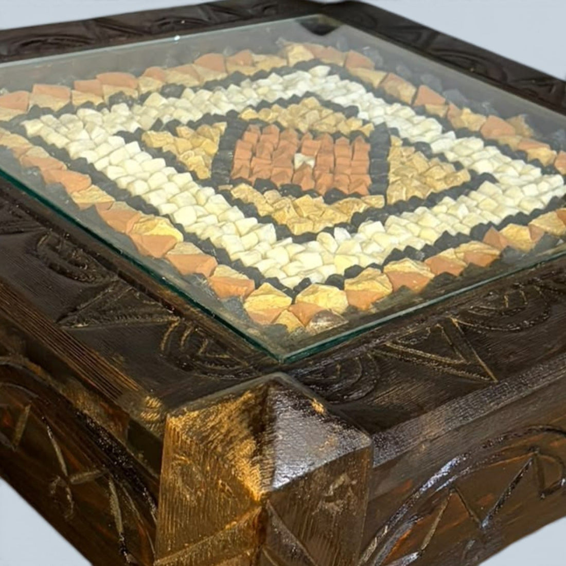 Esta mesa de centro baja de madera tallada con mosaico artesanal de piedra tiene un diseño poco habitual. 
