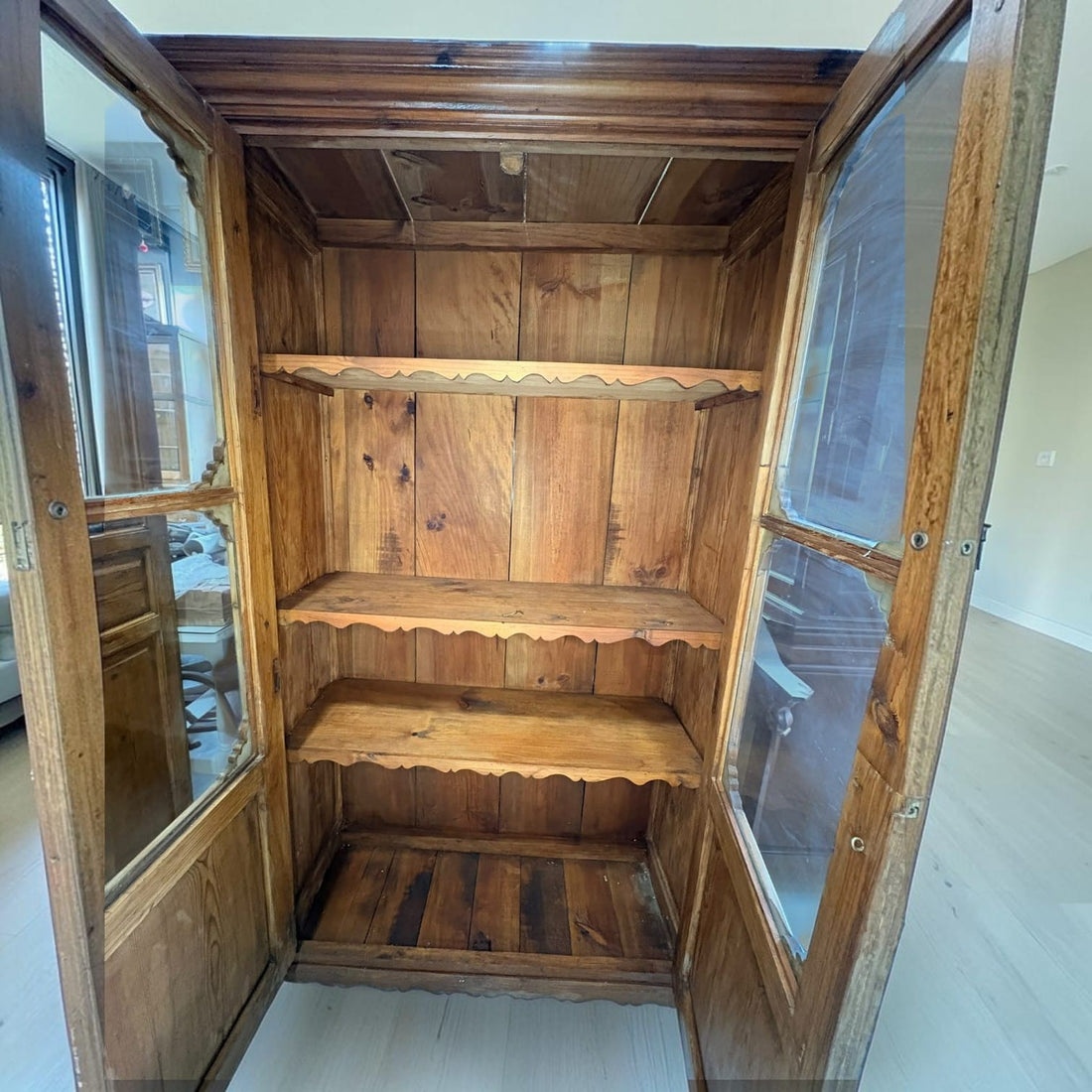 Esta vitrina antigua de madera de estilo rústico combina exposición y almacenaje en un mueble alto de dos puertas.