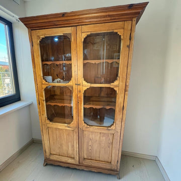 Esta vitrina antigua de madera de estilo rústico combina exposición y almacenaje en un mueble alto de dos puertas.