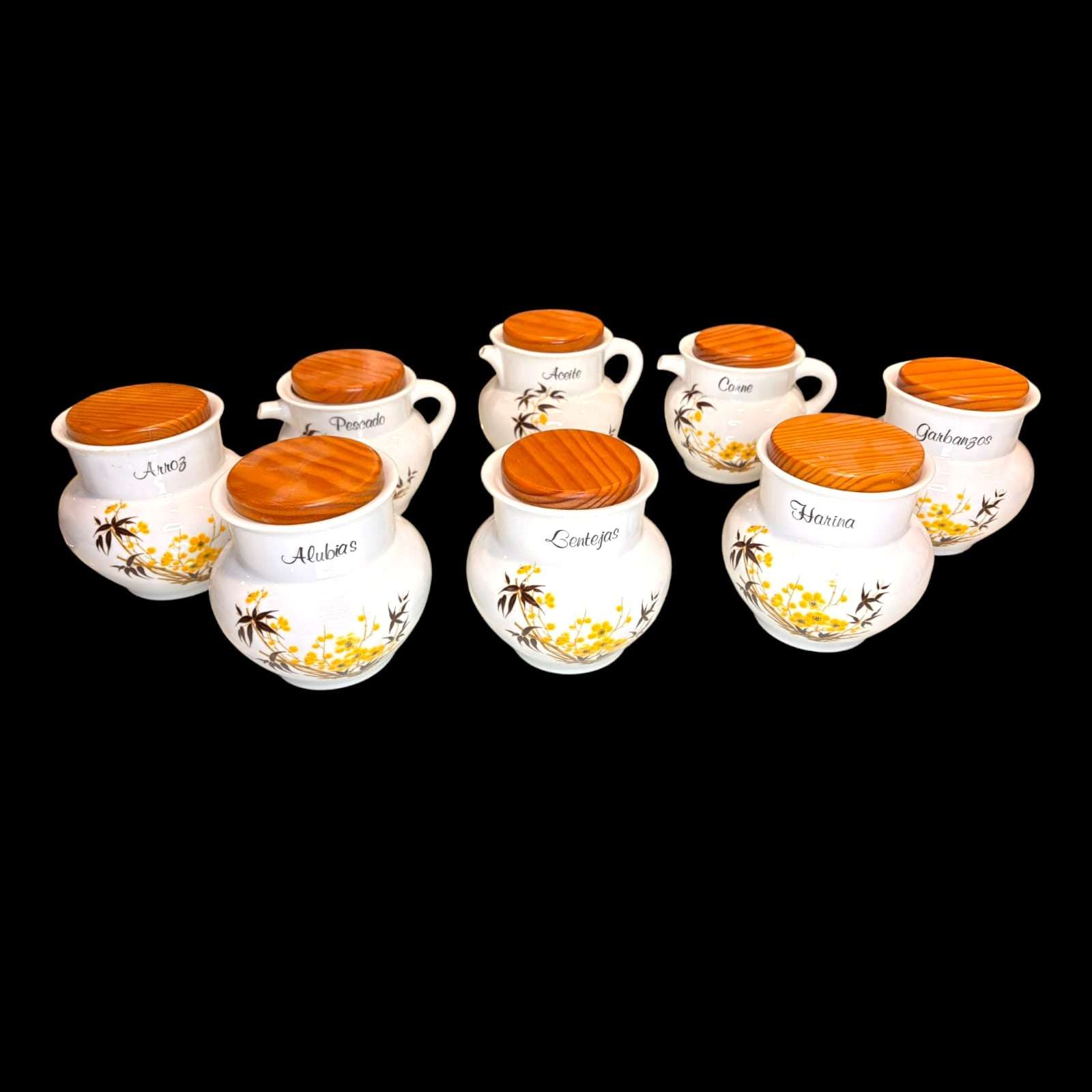 En las imágenes se aprecia una composición muy completa y visualmente armónica, con recipientes rotulados para arroz, alubias, pescado, aceite, carne, lentejas, harina, garbanzos, pimentón, azafrán, vinagre y sal, además de otras piezas auxiliares y soportes de madera. 