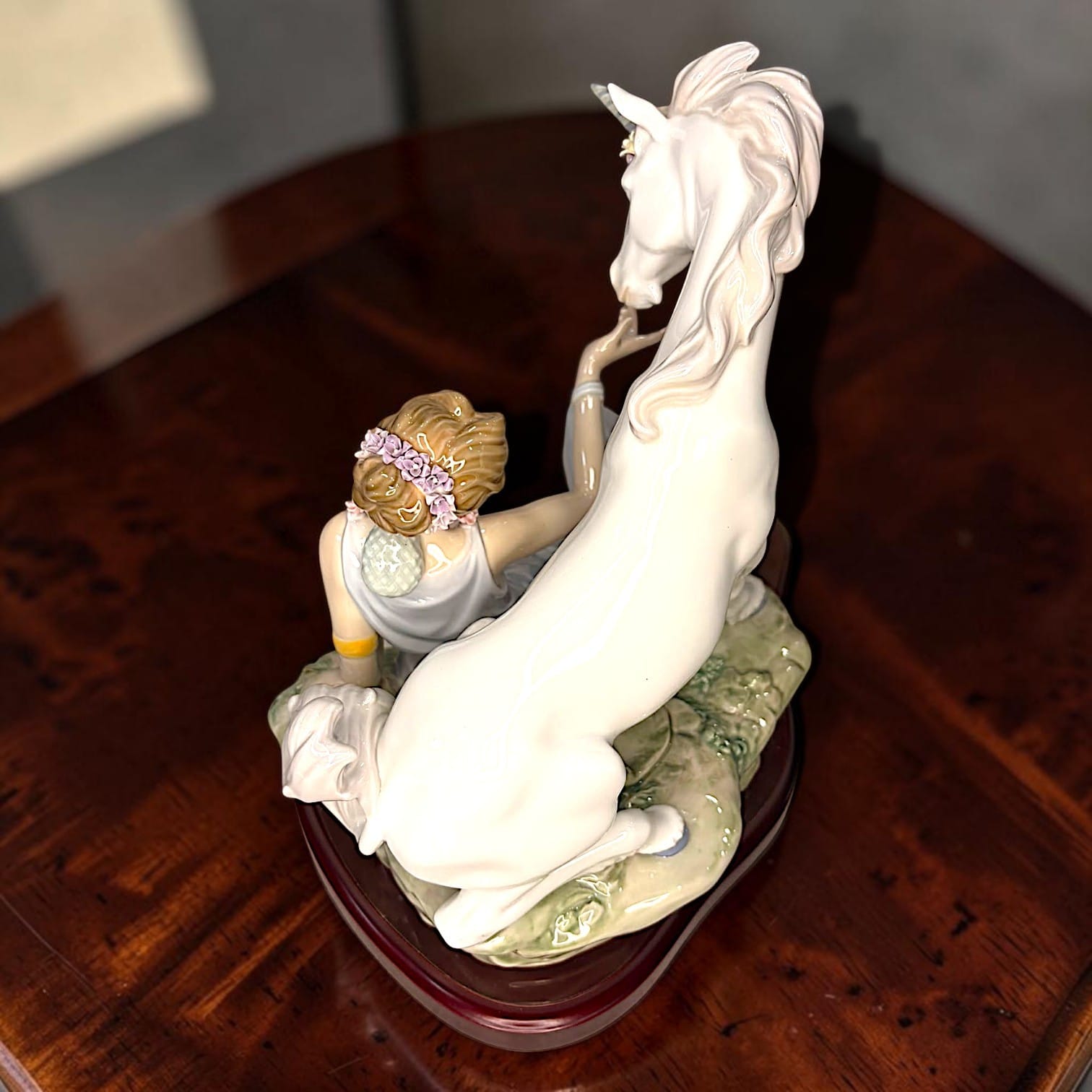  extiende una de sus manos hacia un unicornio situado a su lado.