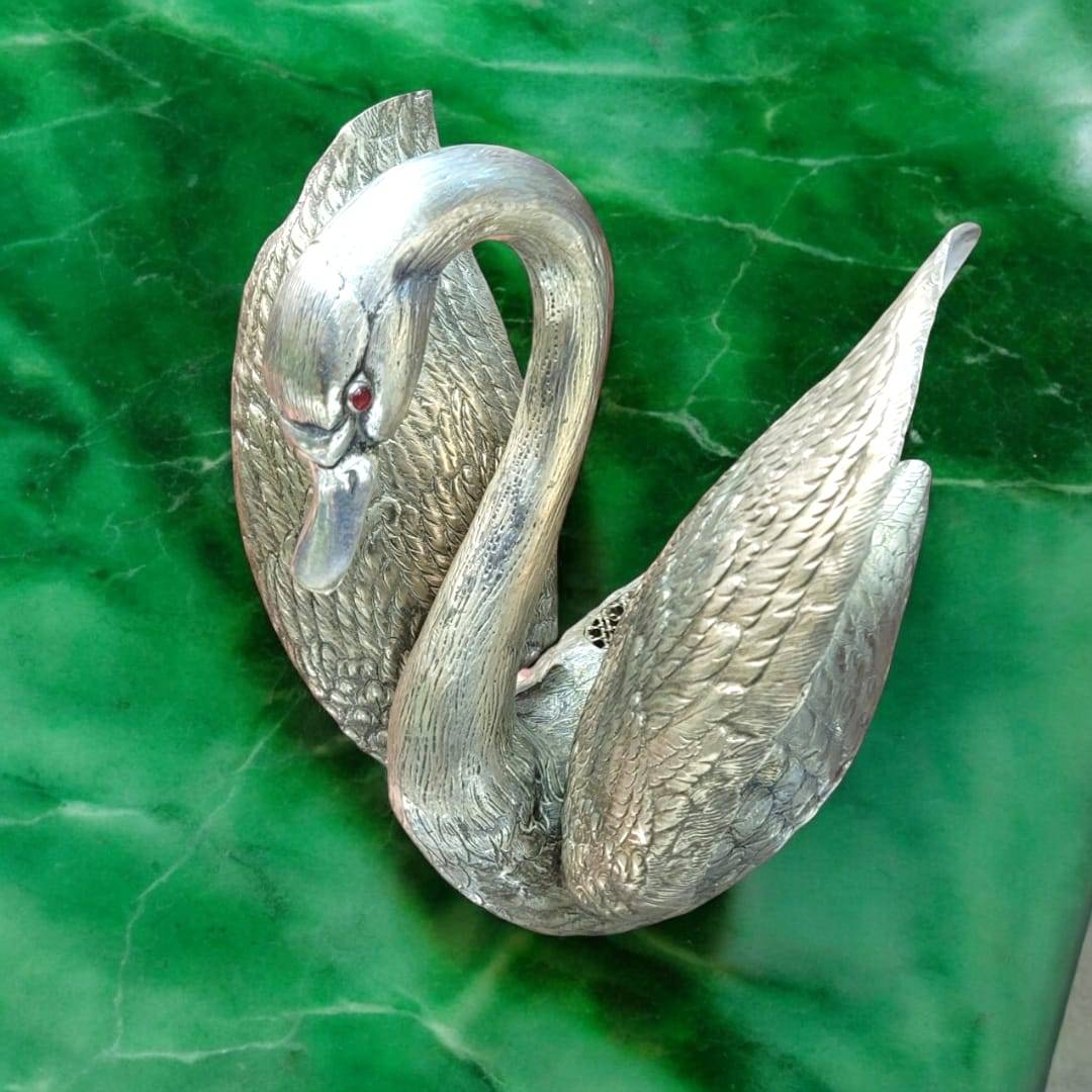 Florero cisne de metal plateado con alas abiertas, ideal para decoración elegante en el hogar. Diseño detallado que simboliza armonía y belleza.