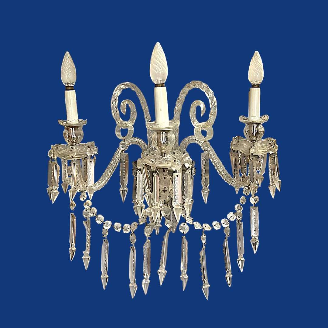 Aplique de cristal de roca antiguo con tres brazos curvos y colgantes tallados, ideal para decoración clásica de interiores elegantes.