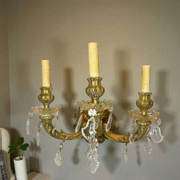 El aplique antiguo de bronce electrificado con lágrimas de cristal es una obra maestra de la iluminación clásica.