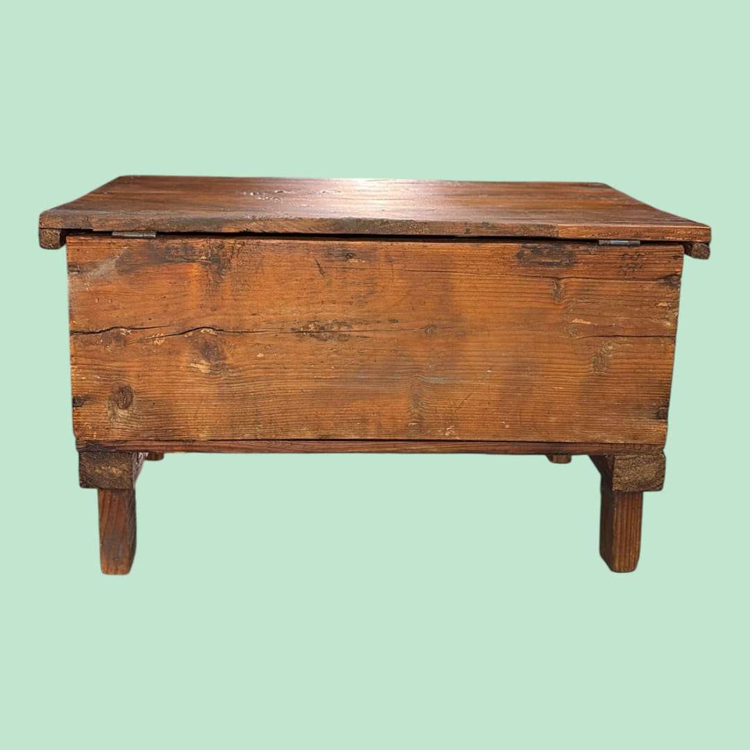 Apoyado sobre cuatro patas macizas, este cofre de madera se eleva ligeramente del suelo, una solución tradicional que ayudaba a proteger su contenido de la humedad. 