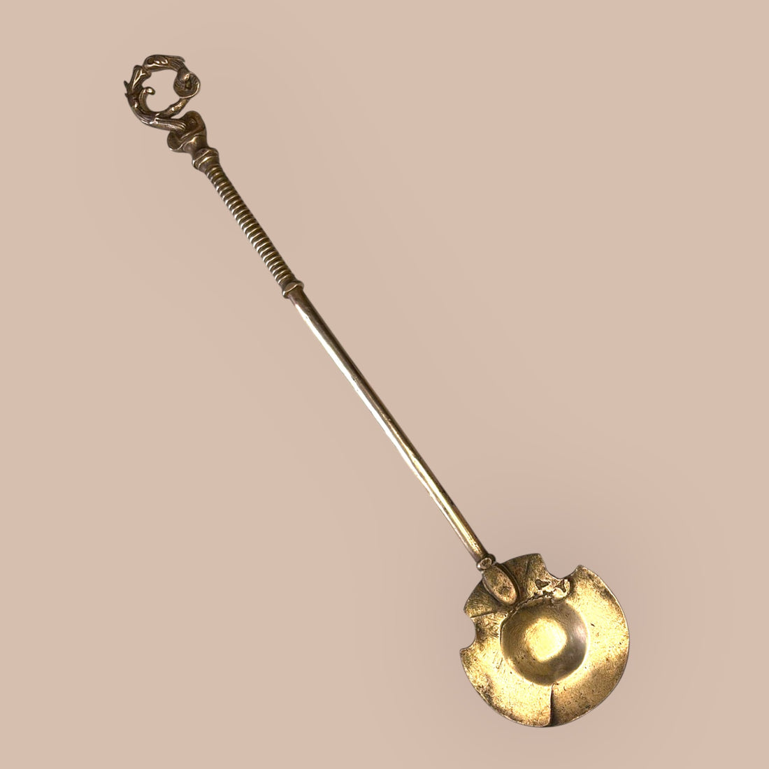 Badila de bronce antigua para brasero tradicional con diseño funcional y decorativo, ideal para manipulación de brasas en decoración rústica.