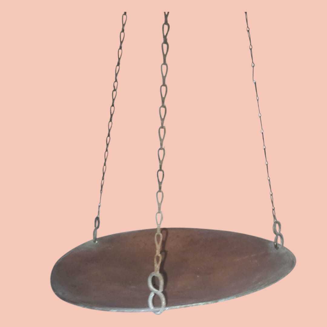 Primer plano del plato metálico colgante sostenido por cadenas de eslabones gruesos.