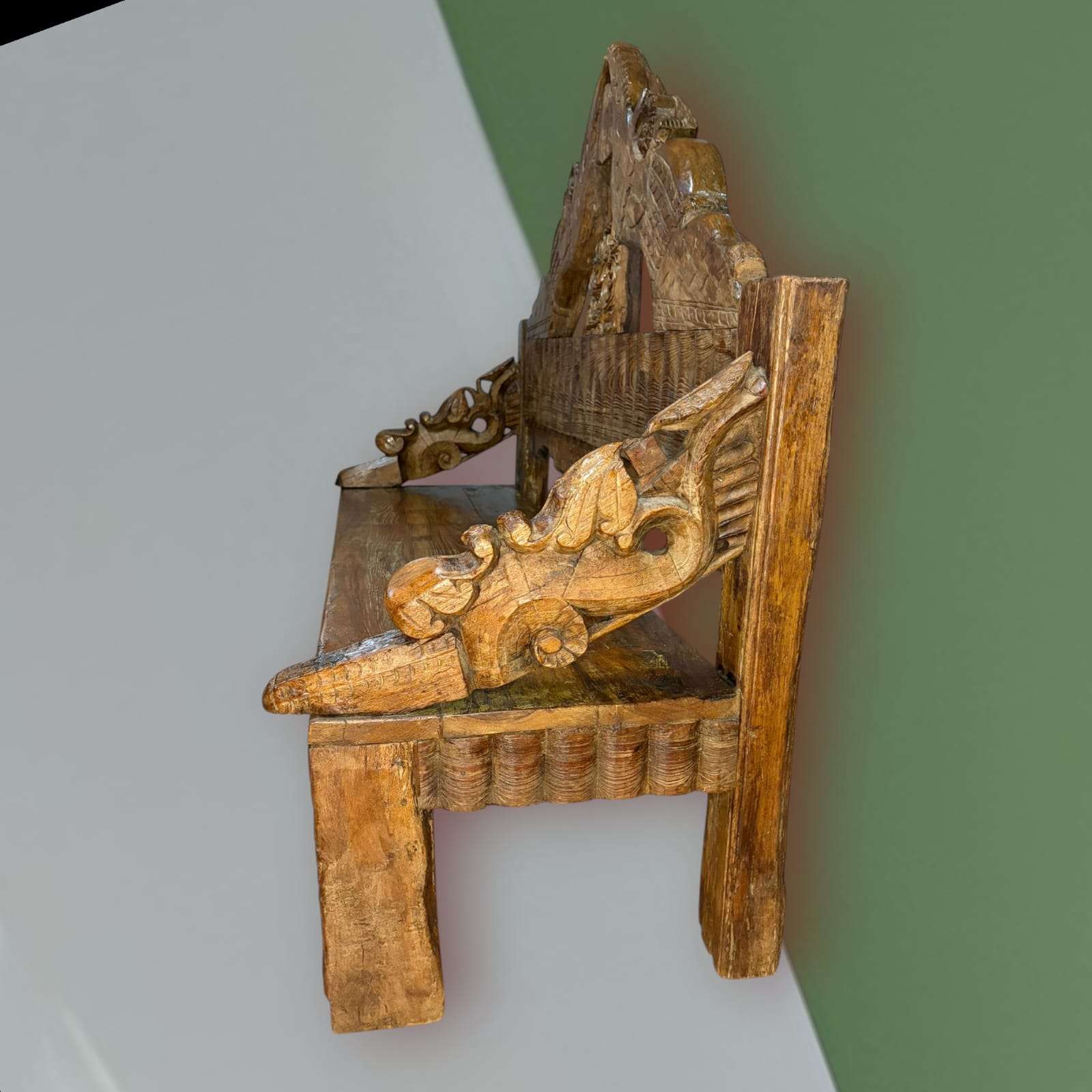 Detalle del respaldo tallado con figuras aladas en banco asiático