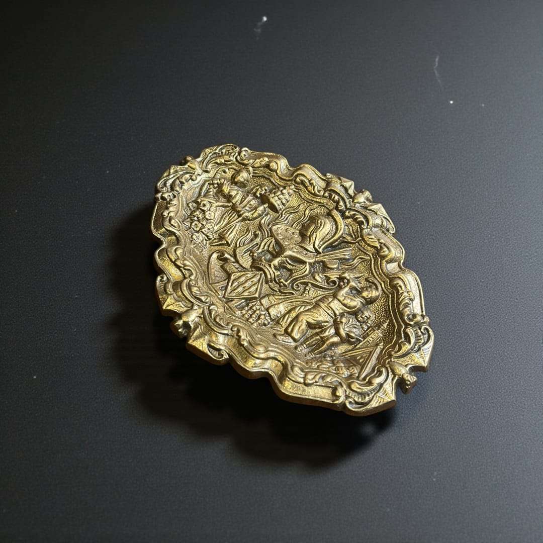 Esta Bandeja de bronce decorativa es una pieza excepcional que destaca por su extraordinario trabajo en relieve y su cuidada composición artística. 